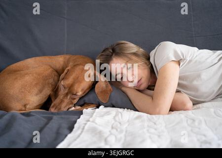 Unglücklich depressive Frau liegend mit Hund zu Hause auf dem Sofa fühlt Apathie hat psychische Probleme. Einsamkeit Stockfoto