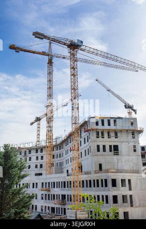 Turmkräne über einem großen Wohngebäude aus Beton im Bau Stockfoto