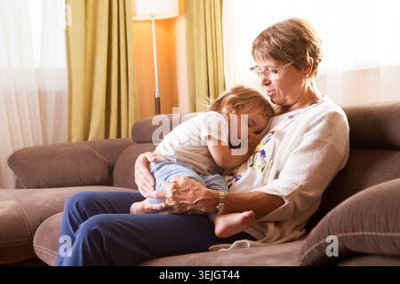 Das Baby schläft in den Händen ihrer Großmutter Stockfoto
