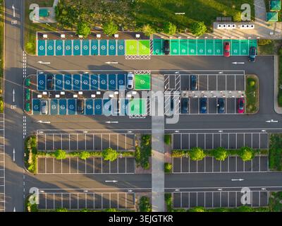 Luftaufnahme der Ladestation für Elektrofahrzeuge bei Rugby Services mit grünen und blauen Parkbuchten und geparkten Autos Rugby, England, Vereinigtes Königreich Stockfoto