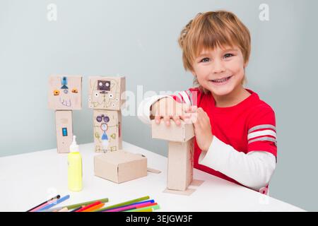 Happy Kid macht den Roboter aus Pappschachteln. Kreativität für Kinder. Stockfoto