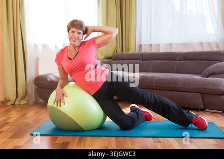 Fröhliche Seniorin, die im Haus Übungen macht Stockfoto