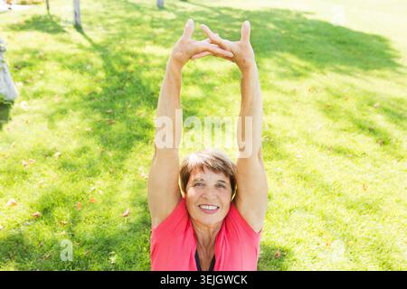 Frau, die Yoga auf grünem Gras im Park macht. Stockfoto