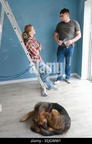 Glückliches Paar, das eine neue Wohnung renoviert und zusammen die Wand malte. Familie Mann Frau repariert flach. Stockfoto