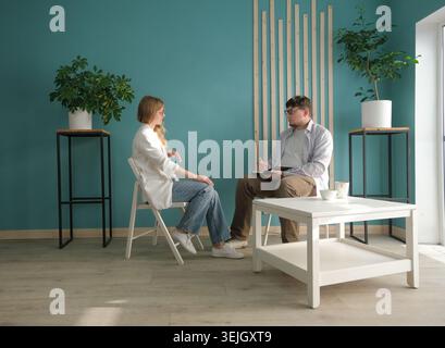 Geschäftsleute, die sich zu Hause unterhalten, häusliche Beratung. Anwalt oder Psychologe, der in freundlicher Umgebung spricht Stockfoto