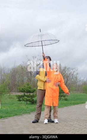 Glückliches Paar, das an einem regnerischen Tag im Park spaziert Stockfoto
