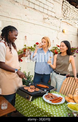 Verschiedene Freundinnen, die im Sommer eine Grillparty mit Wein genießen Stockfoto
