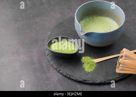 Traditionelles grünes Matcha-Set, Bambusquirl und Getränk auf Schieferplatte, dunkler Hintergrund mit Kopierraum Stockfoto