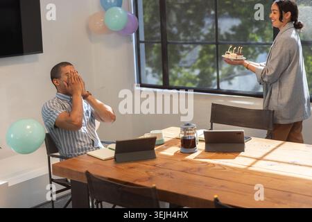 Verschiedene Mitarbeiterinnen feiern Geburtstag im Konferenzraum mit Kuchen und Ballons, Kopierraum. Feiern, Professionalität, Stockfoto