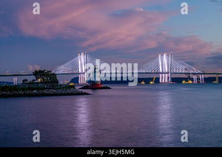 Aus der Vogelperspektive auf den Sleepy Hollow Lighthouse und die beleuchtete Governor Mario M. Cuomo Bridge unter einem violetten Sonnenuntergang über dem Fluss in Sleepy Holl Stockfoto