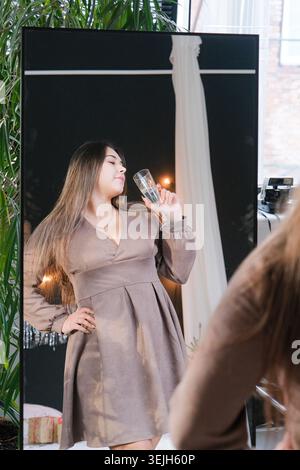 Frau in grauem Kleid, die auf der Party steht und Champagner trinkt Stockfoto