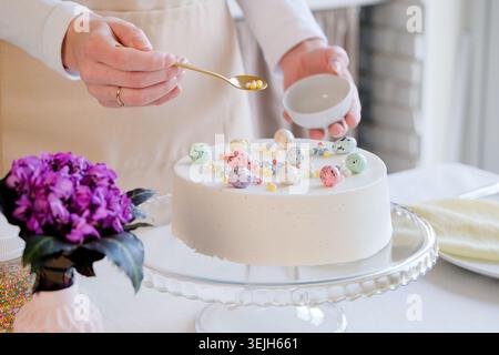 Junge Frau, die Osterkuchen mit Streuseln in der Küche dekoriert Stockfoto