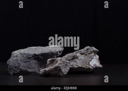 Graues Marmorstein Podium für Verpackung und kosmetische Präsentation auf schwarzem Hintergrund, Kopierraum. Natürlicher und starker Style. Stockfoto