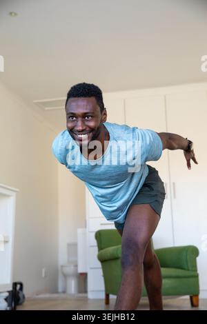 Afroamerikaner in Sportbekleidung, der zu Hause mit einer Kettlebell Balanceübung auf einem Bein ausübt. Fitness, Wellness, Home Wor Stockfoto