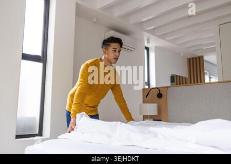 Asiatisches Bett in hellem, modernem Schlafzimmer mit weißer Bettwäsche, grauem Kopfteil und geteilter Klimaanlage. Minimalistisch, modern, gemütlich, innen, Lifestyle, r Stockfoto