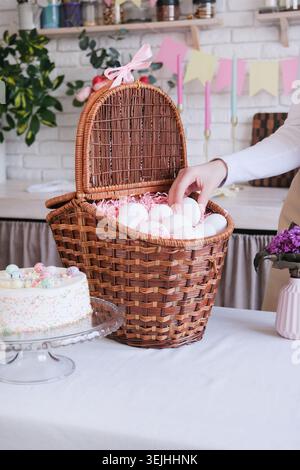 Unerkennbare Frau in Schürze, die weißen Eier in den Korb, bereit für Ostern, Eiermockup Stockfoto