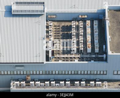 Luftaufnahme der mehrreihigen Industrieklimaanlagen und HLK-Systeme, die auf dem Wellblechdach eines großen Gewerbes installiert sind Stockfoto