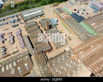 Blick aus der Vogelperspektive auf Kingsbury Brick Works and Factory mit großen industriellen Lagerhäusern, einem hohen Ziegelkamin und Stapeln von Baumaterialien in Dost Stockfoto