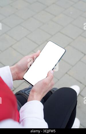 Frau, die Knie- oder Orthesen nach einer Beinoperation trägt, im Park sitzt Stockfoto
