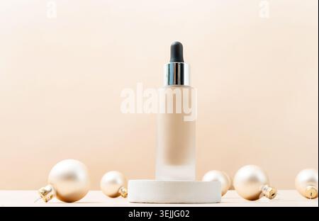 Eine minimalistische Szene mit einer Grundierflasche auf dem Podium mit dekorativen weihnachtskugeln auf beigem Hintergrund Stockfoto