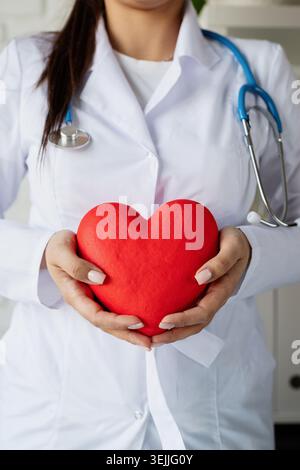 Doktor oder Wissenschaftlerin, die großes rotes Herz in Händen hält Stockfoto