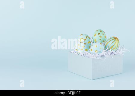 Handgefertigte blaue ostereier mit goldenem Glitzer-Design in Geschenkbox auf blauem Hintergrund. Stockfoto