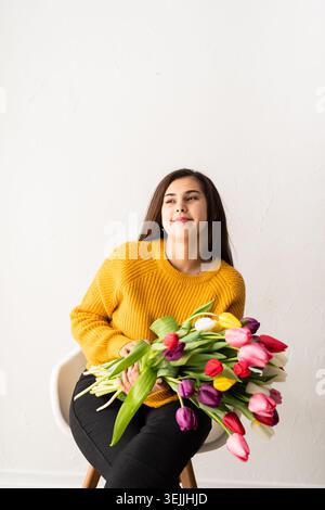 Schöne junge brünette Frau mit einem Strauß frischer rosa Tulpen Stockfoto