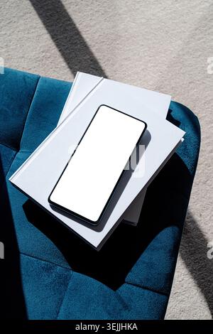 Smartphone mit isoliertem Bildschirm auf blauem Stuhl. Im Innenraum zu Hause. Stockfoto