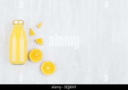 Frischer Fruchtfleisch gelber Orangensaft in Glasflasche mit geschnittenem Obst als Modell für Werbung, Portfolio, Design-Draufsicht auf weiß Stockfoto