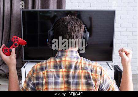Rückansicht eines jungen Mannes, der zu Hause Videospiele spielt Stockfoto