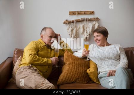 Seniorenpaar trinken Wein auf einem Sofa zu Hause. Stockfoto