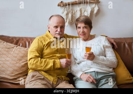 Seniorenpaar trinken Wein auf einem Sofa zu Hause. Stockfoto