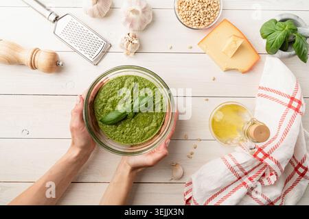 Zubereitung italienischer Pesto-Sauce. Frauenhände halten hausgemachte Pesto-Schüssel Stockfoto