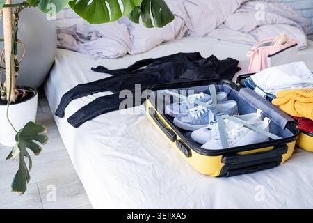 Koffer für Reisen packen, zu Hause auf dem Bett sitzen Stockfoto