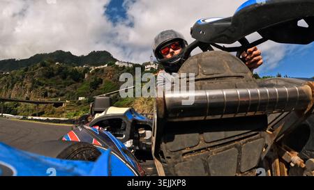 Gokart-Fahrer mit Helm und Sonnenbrille auf einer Rennstrecke in den Bergen von madeira Stockfoto