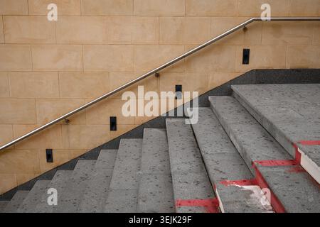 Hochwinkelaufnahme von architektonischen Betonstufen mit Sicherheitsgeländer aus Metall und beigefarbener Wand Stockfoto