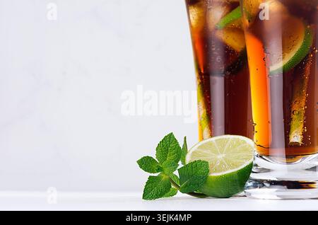 Coole Cocktail-Rum und Cola in eleganten, langen Gläsern mit Luftblasen und Eiswürfeln in sanftem, hellweißem Innenraum. Kopierraum, Nahaufnahme. Stockfoto