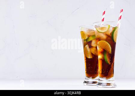 Coole Cocktail-Rum und Cola in eleganten, langen Gläsern mit Luftblasen und Eiswürfeln in sanftem, hellweißem Innenraum. Kopierbereich. Stockfoto