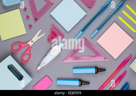 Zurück zum Schulhintergrund - farbige Schreibwaren auf grauem Tischhintergrund, Draufsicht, Muster. Stockfoto