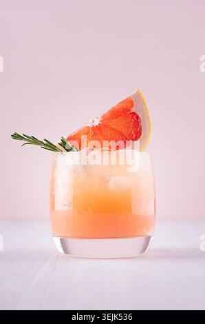 Kalter Detox Cocktail aus Grapefruitsaft mit Eis, Rosmarin, Scheiben Zitrusfrüchten auf weichem hellrosa und weißem Hintergrund. Stockfoto