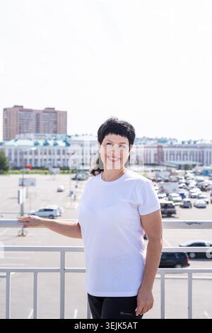Lächelnde Seniorin, die draußen auf urbanem Hintergrund arbeitet Stockfoto