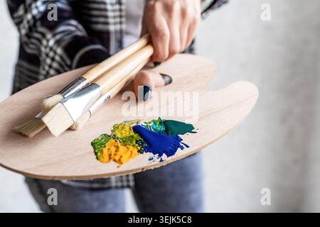 Nahaufnahme von Künstlerhänden, die Holzkunstpalette und Pinsel halten Stockfoto