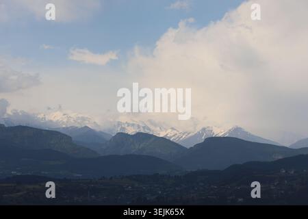 Schneebedeckte Berggipfel, Die Hinter Dunklen Silhouettenkämmen Unter Bewölktem Himmel Liegen Stockfoto