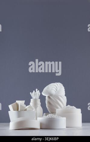 Weiße Kosmetikprodukte in verschiedenen weißen Schalen auf Holztisch und grauer Wand mit Kopierraum, Nahaufnahme. Stockfoto