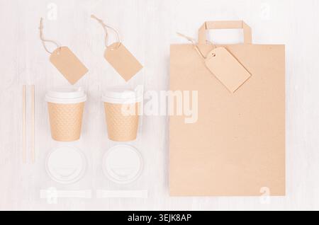 Coffee Branding Identity Mockup - Set aus zwei braunen Pappbechern mit leerem Beutel, Etikett, Kappe, Zucker auf weißem Holzbrett, Draufsicht. Stockfoto