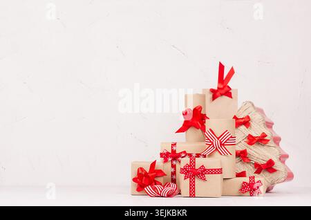 Handgemachte weihnachtsgeschenke von Kraft und weihnachtsbaum von mit festlichen roten Bändern und Bögen auf weißem Holzhintergrund. Stockfoto