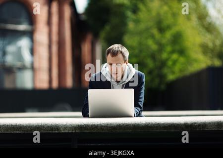 Gelegenheitsunternehmer, der an einem Laptop im Freien an einer Startup-Idee oder einer Projektentwicklungsstrategie arbeitet Stockfoto