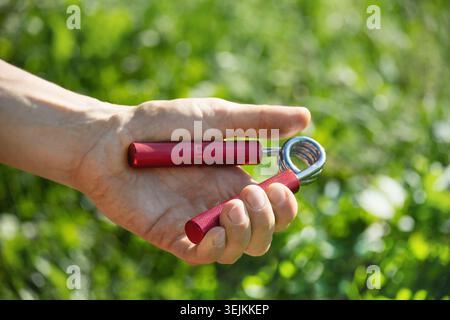 Er hat roten Metallexpander in der Hand des Mannes. Stockfoto