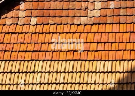 Texturhintergrund verwitterter orangener Tonfliesen auf einem alten Hüttendach. Stockfoto