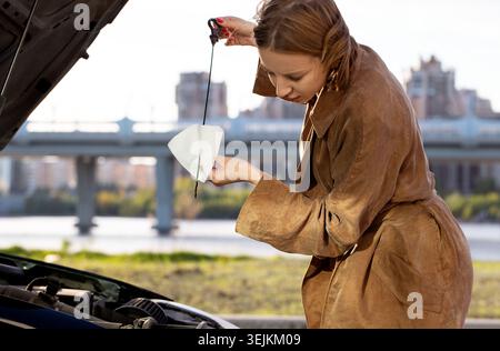 Selbstbewusste kaukasische Fahrerin, die den Ölstand im Peilstab überprüft Stockfoto